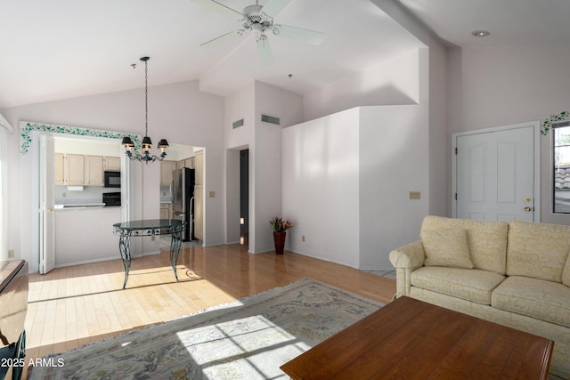 living room featuring ceiling fan with notable chandelier, high vaulted ceiling, and light wood-type flooring