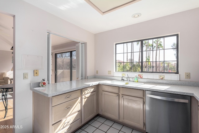 kitchen with dishwasher, kitchen peninsula, sink, light stone countertops, and light tile patterned floors