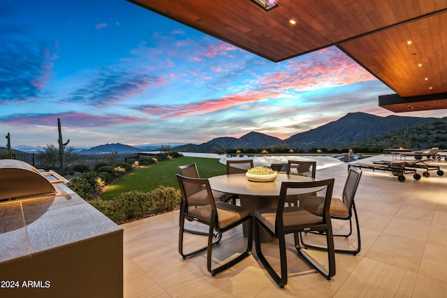 patio terrace at dusk with exterior kitchen and a mountain view