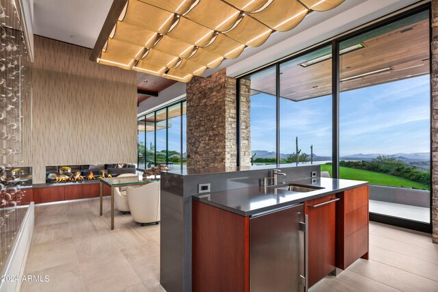 kitchen featuring a center island with sink, floor to ceiling windows, a mountain view, and sink