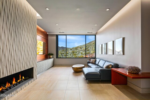 interior space with a large fireplace, a mountain view, light tile patterned floors, and a wall of windows