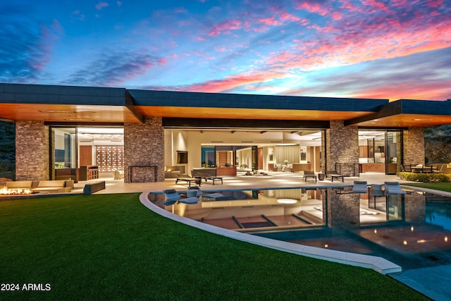 back house at dusk featuring a patio area and a yard