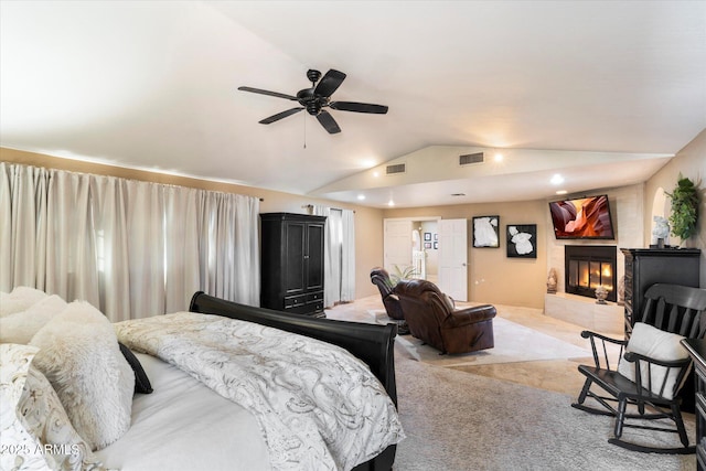 carpeted bedroom featuring a tiled fireplace, lofted ceiling, and ceiling fan