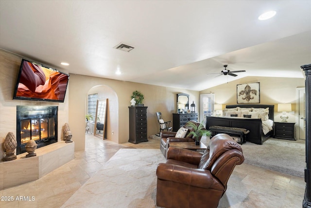 bedroom with lofted ceiling, a tile fireplace, and ceiling fan