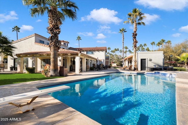 view of pool with a diving board and a patio