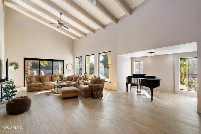 living room with beam ceiling, ceiling fan, light wood-type flooring, and high vaulted ceiling