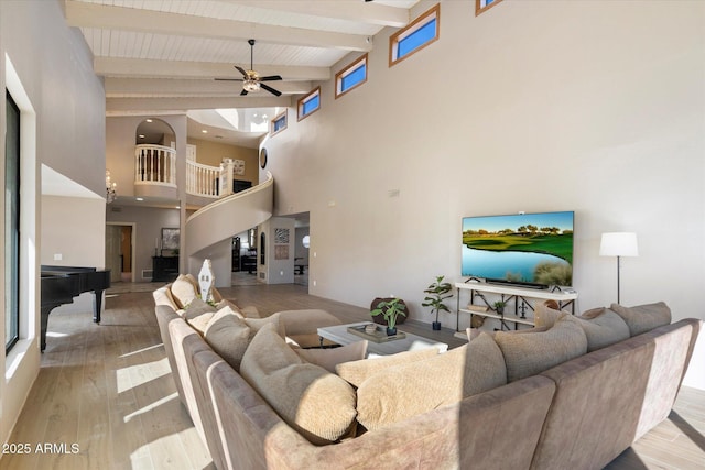 living room featuring beam ceiling, a wealth of natural light, light hardwood / wood-style floors, and a high ceiling