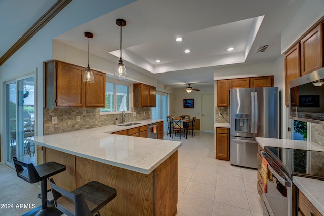 kitchen with sink, appliances with stainless steel finishes, tasteful backsplash, kitchen peninsula, and a breakfast bar area