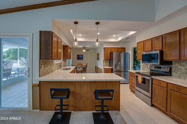 kitchen featuring kitchen peninsula, appliances with stainless steel finishes, a kitchen bar, vaulted ceiling, and pendant lighting