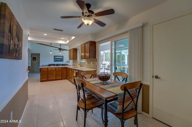 dining room with ceiling fan, light tile patterned floors, sink, and a tray ceiling