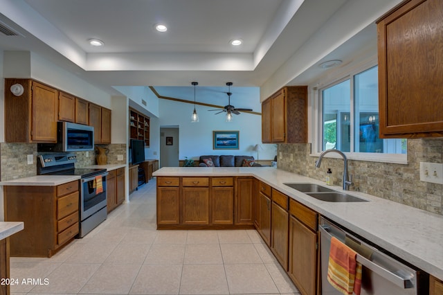 kitchen with kitchen peninsula, backsplash, stainless steel appliances, sink, and decorative light fixtures