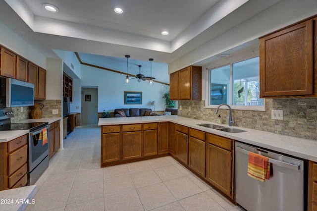 kitchen with sink, hanging light fixtures, kitchen peninsula, decorative backsplash, and appliances with stainless steel finishes