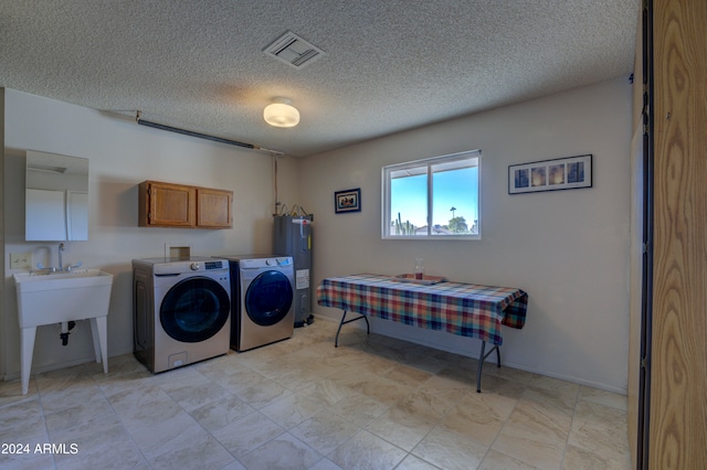 laundry room with washing machine and dryer, electric water heater, cabinets, and a textured ceiling