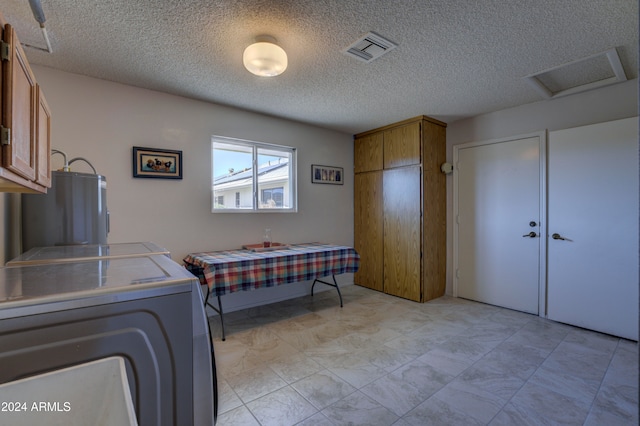 washroom featuring cabinets, a textured ceiling, and washing machine and dryer