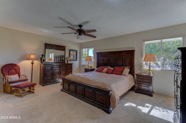 bedroom featuring a textured ceiling, light colored carpet, and ceiling fan