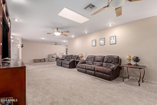 living room featuring a skylight, light carpet, and ceiling fan