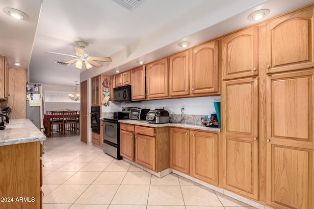 kitchen with light stone counters, light tile patterned floors, black appliances, and ceiling fan with notable chandelier