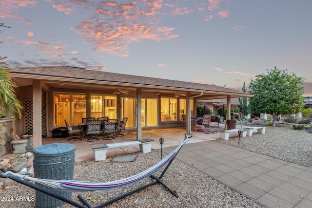 back house at dusk featuring ceiling fan and a patio area