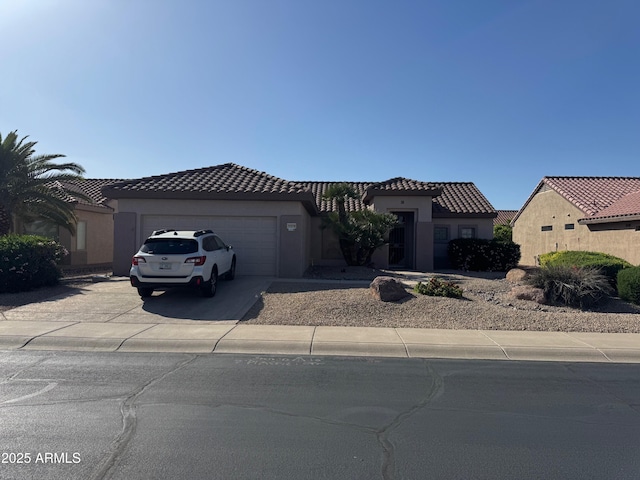 view of front of property featuring a garage, concrete driveway, a tiled roof, and stucco siding