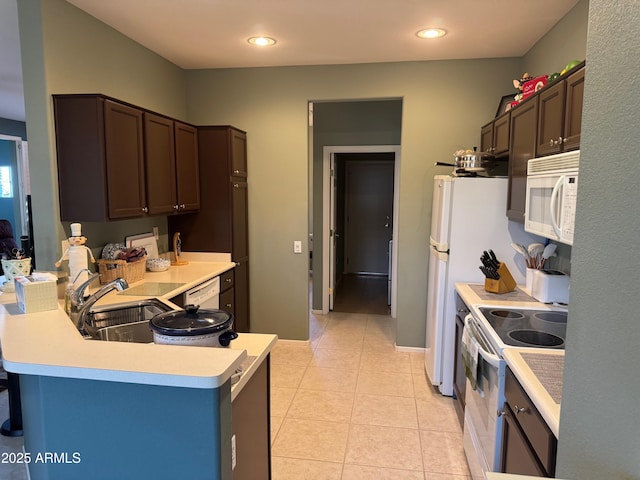 kitchen featuring white appliances, light tile patterned floors, dark brown cabinetry, light countertops, and a peninsula