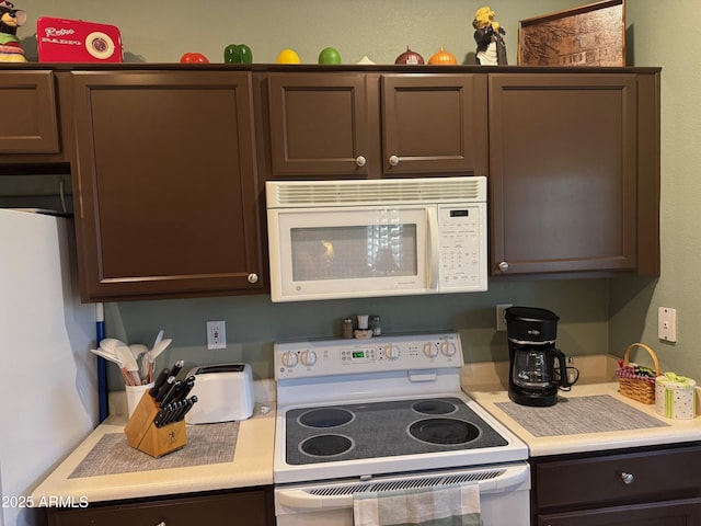 kitchen featuring dark brown cabinets, white appliances, and light countertops