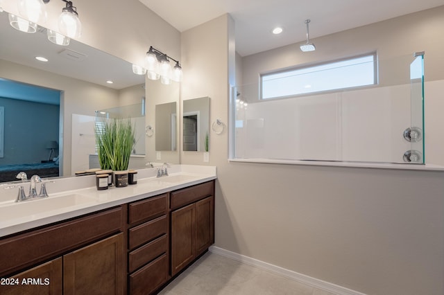 bathroom with a walk in shower, double vanity, a sink, and baseboards