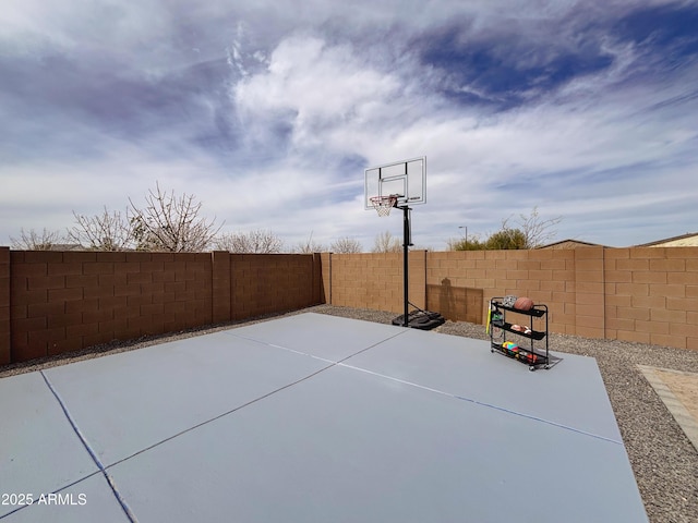 view of sport court with a fenced backyard and basketball hoop