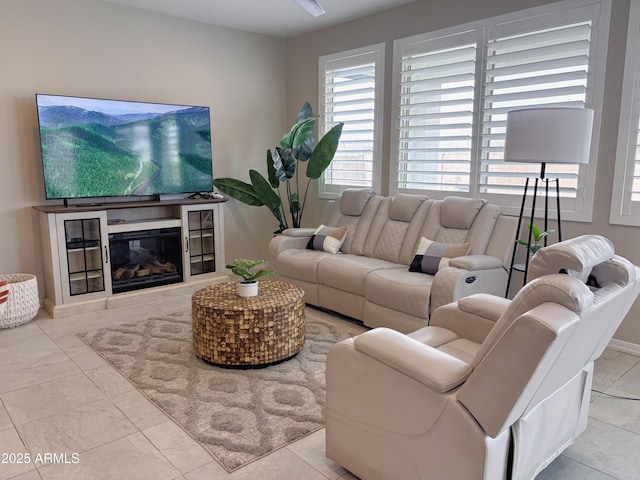 tiled living area featuring plenty of natural light and a glass covered fireplace