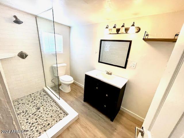 bathroom with hardwood / wood-style floors, vanity, toilet, and walk in shower