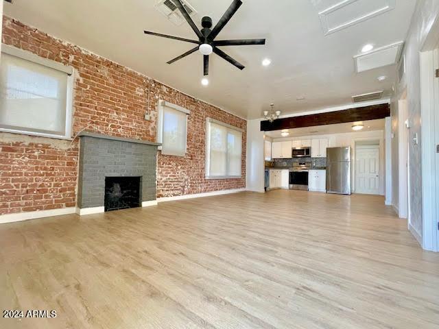 unfurnished living room featuring a fireplace, light hardwood / wood-style flooring, ceiling fan, and brick wall