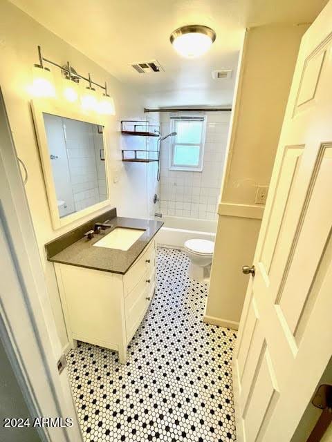 full bathroom with tiled shower / bath, tile patterned flooring, vanity, and toilet