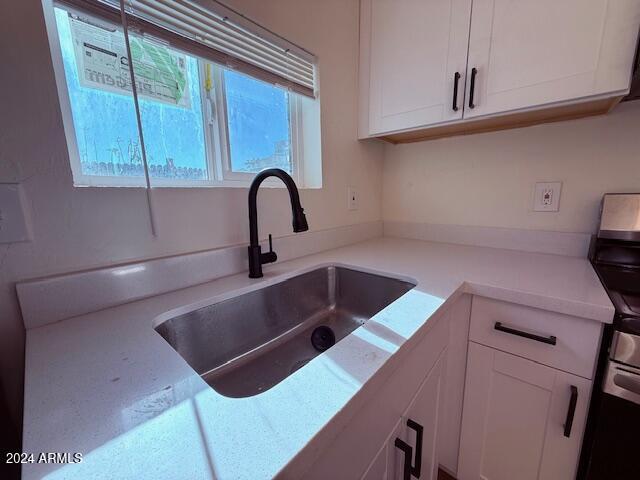 kitchen with white cabinets, sink, and stainless steel range with electric cooktop