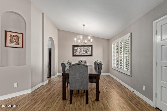 821 E Chicago St, Chandler, AZ 85225 - dining room featuring a notable chandelier, arched walkways, baseboards, wood finished floors, and vaulted ceiling