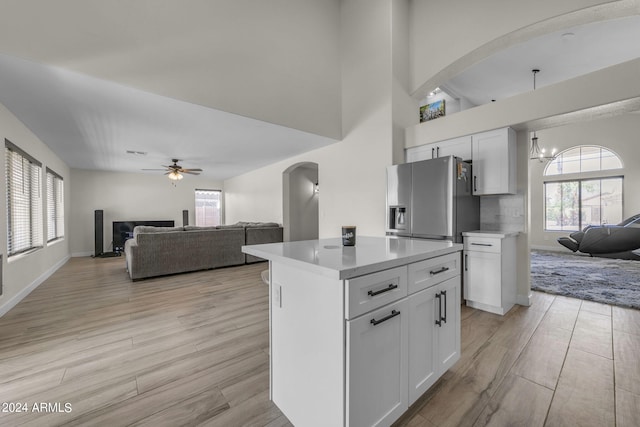 kitchen with white cabinetry, stainless steel refrigerator with ice dispenser, a kitchen island, and light hardwood / wood-style floors