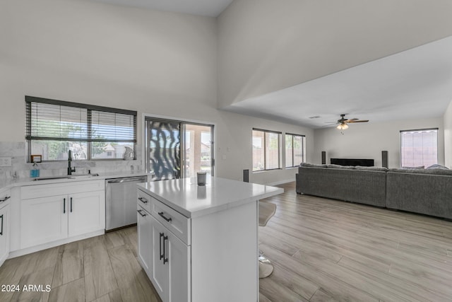 kitchen featuring a kitchen island, white cabinetry, dishwasher, sink, and light hardwood / wood-style flooring