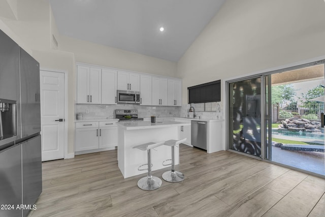 kitchen with sink, stainless steel appliances, a center island, tasteful backsplash, and white cabinets