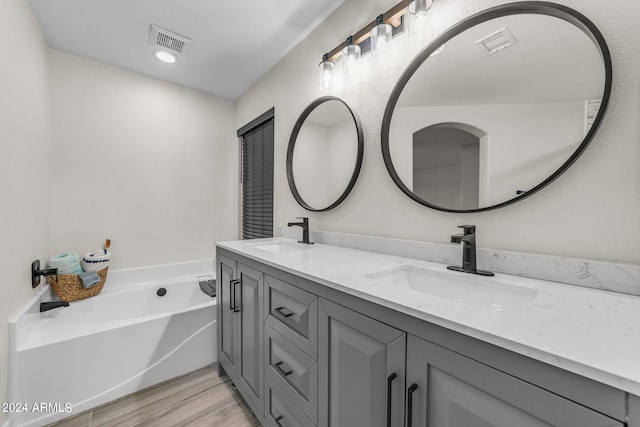 bathroom with vanity, hardwood / wood-style floors, and a bathtub