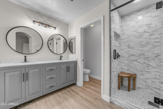 bathroom featuring hardwood / wood-style flooring, vanity, toilet, and a shower with door