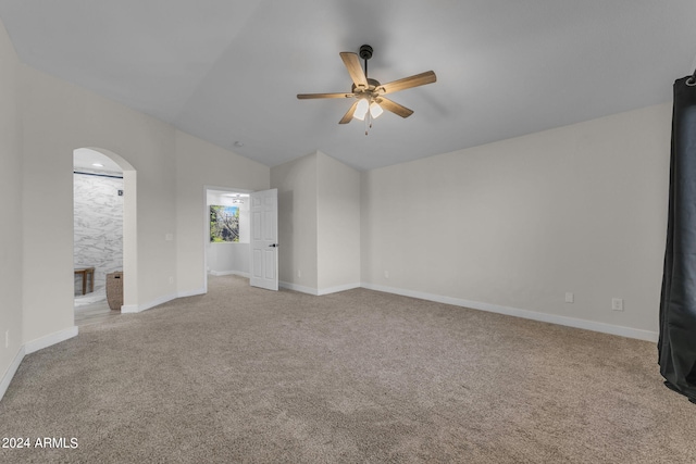 carpeted spare room featuring ceiling fan and vaulted ceiling