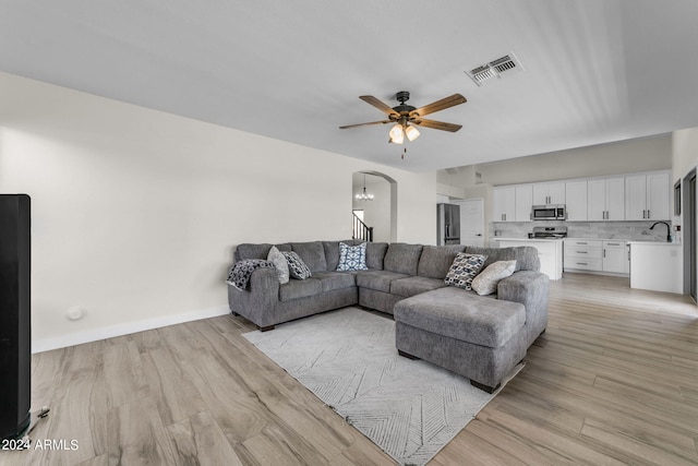 living room featuring sink, ceiling fan with notable chandelier, and light wood-type flooring