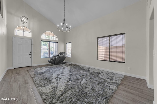 foyer with wood-type flooring, high vaulted ceiling, and a chandelier