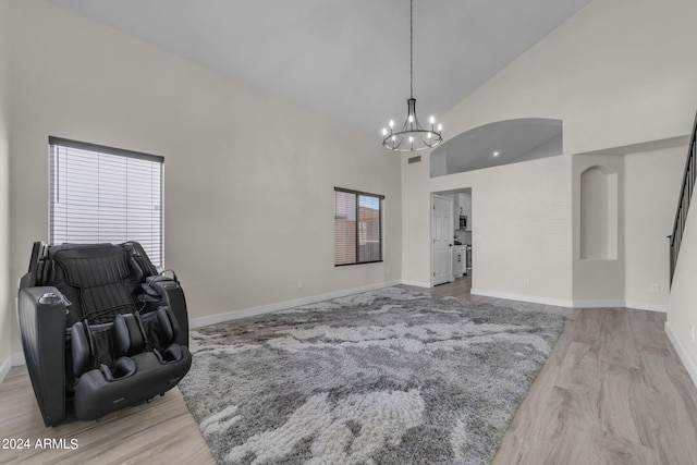 living room with an inviting chandelier, high vaulted ceiling, and light hardwood / wood-style floors