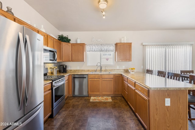 kitchen featuring kitchen peninsula, stainless steel appliances, a breakfast bar area, and sink