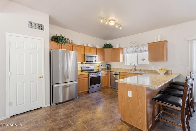 kitchen with kitchen peninsula, a kitchen breakfast bar, decorative backsplash, stainless steel appliances, and sink