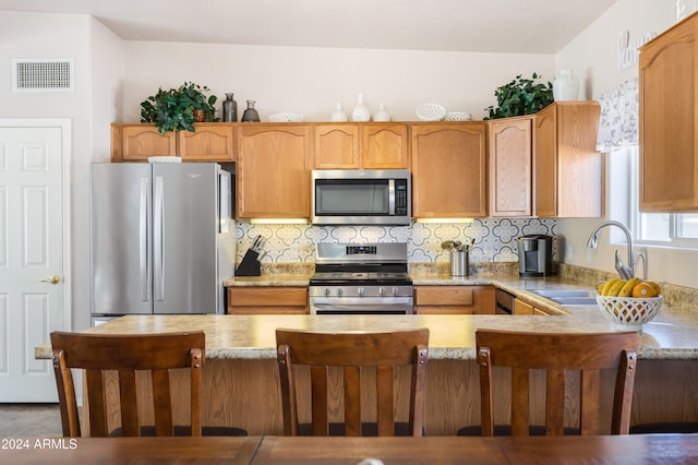 kitchen featuring tasteful backsplash, kitchen peninsula, sink, and appliances with stainless steel finishes