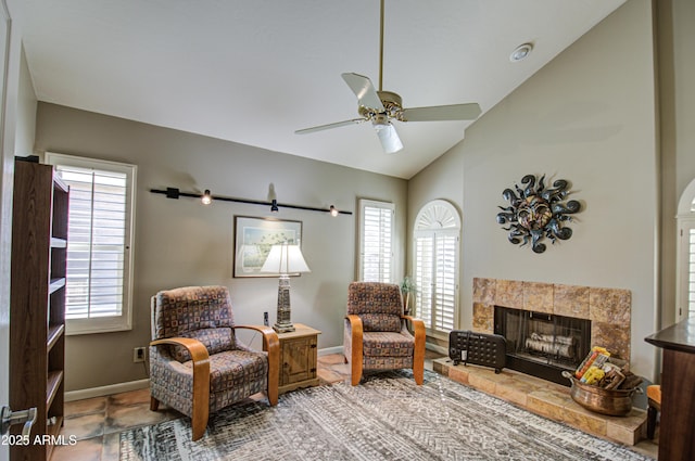 sitting room with ceiling fan, lofted ceiling, and a tiled fireplace