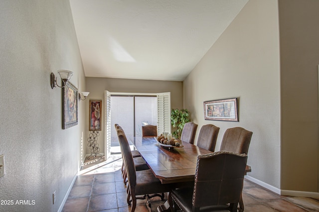 dining room featuring vaulted ceiling and light tile patterned flooring