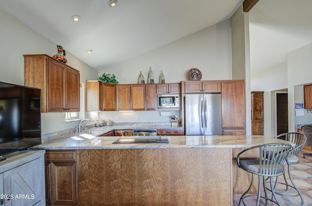 kitchen featuring a breakfast bar, sink, appliances with stainless steel finishes, kitchen peninsula, and light stone countertops