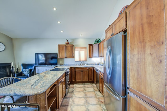 kitchen with sink, stainless steel appliances, a kitchen breakfast bar, light stone counters, and kitchen peninsula