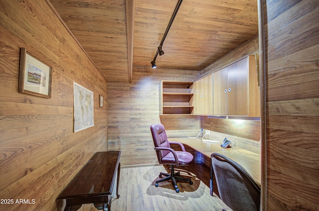 unfurnished office with built in desk, wooden walls, track lighting, wooden ceiling, and light wood-type flooring